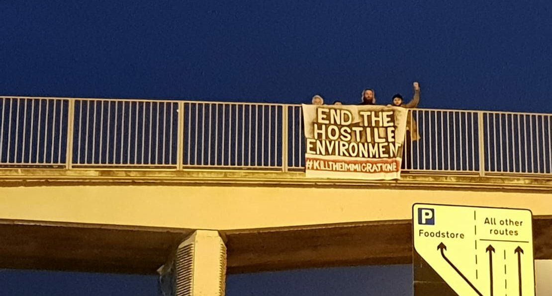 Activists drop a banner reading "End the hostile environment - kill the immigration bill" from a motorway bridge