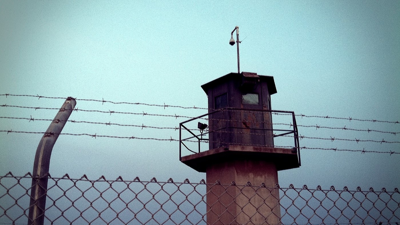 Photo of a watch-tower behind a barbed-wire fence