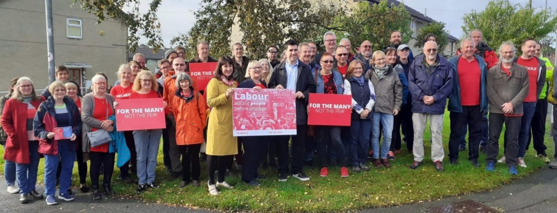 Labour campaigners gathered in a line, behind signs reading "For the many not the few", with Rachel Reeves MP near the middle holding a sign reading "Labour will put people before privilege"